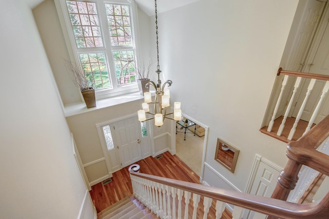 foyer featuring stairs, a chandelier, wood finished floors, and baseboards