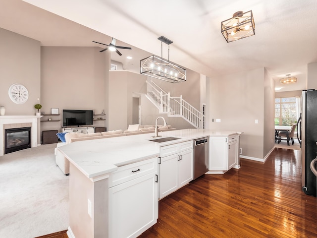kitchen with a sink, open floor plan, ceiling fan, stainless steel appliances, and a tile fireplace