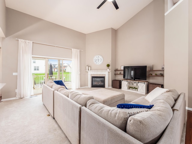 living room with baseboards, ceiling fan, high vaulted ceiling, light colored carpet, and a tile fireplace