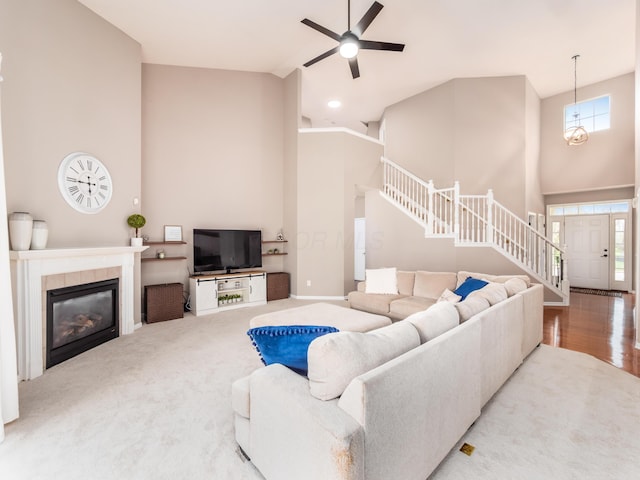 living room with baseboards, a ceiling fan, a fireplace, stairs, and high vaulted ceiling