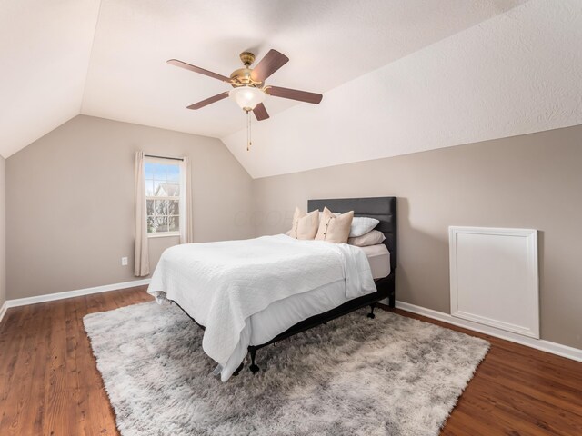 bedroom featuring lofted ceiling, baseboards, and wood finished floors