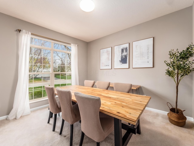 dining area featuring baseboards and light carpet