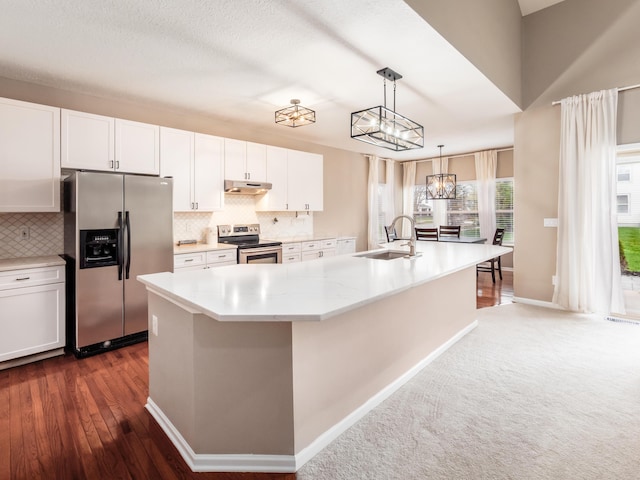 kitchen featuring tasteful backsplash, white cabinetry, under cabinet range hood, a sink, and stainless steel appliances