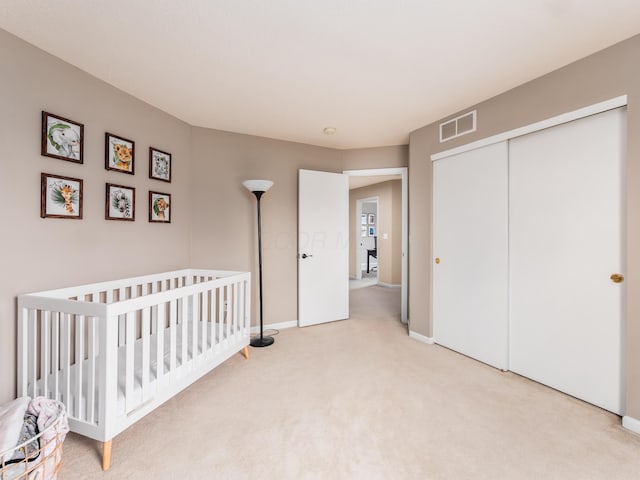 bedroom with light carpet, a closet, baseboards, and visible vents