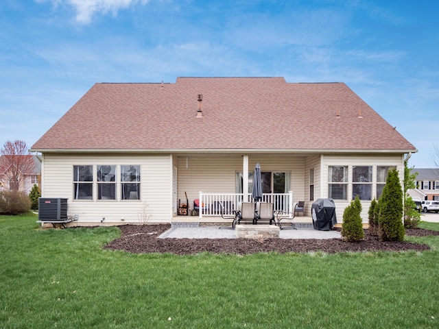 rear view of property featuring a patio, central AC, roof with shingles, and a lawn