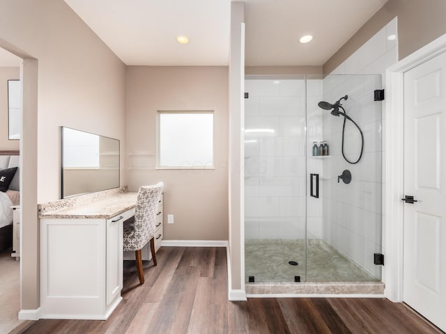 bathroom with ensuite bathroom, baseboards, vanity, wood finished floors, and a stall shower