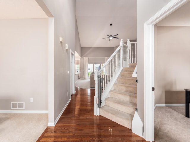 staircase featuring visible vents, baseboards, a ceiling fan, and wood finished floors