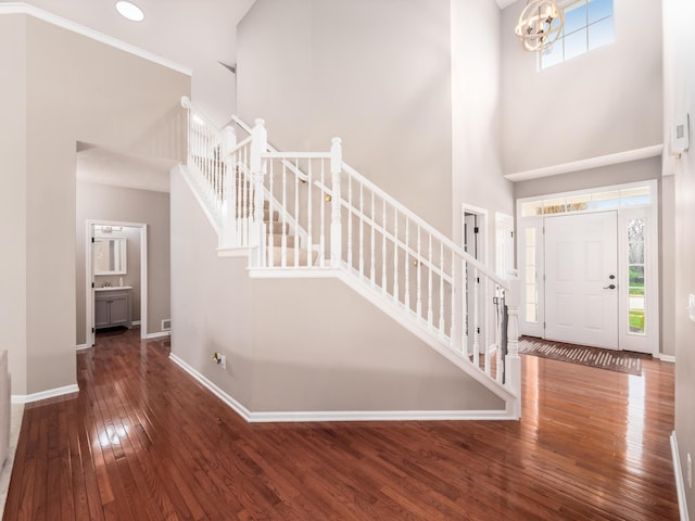 entryway with wood-type flooring, a towering ceiling, baseboards, and stairway