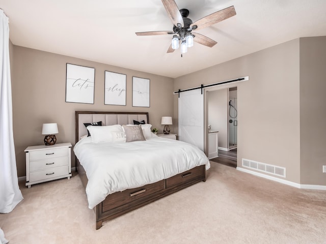 bedroom with visible vents, baseboards, a barn door, a ceiling fan, and light carpet