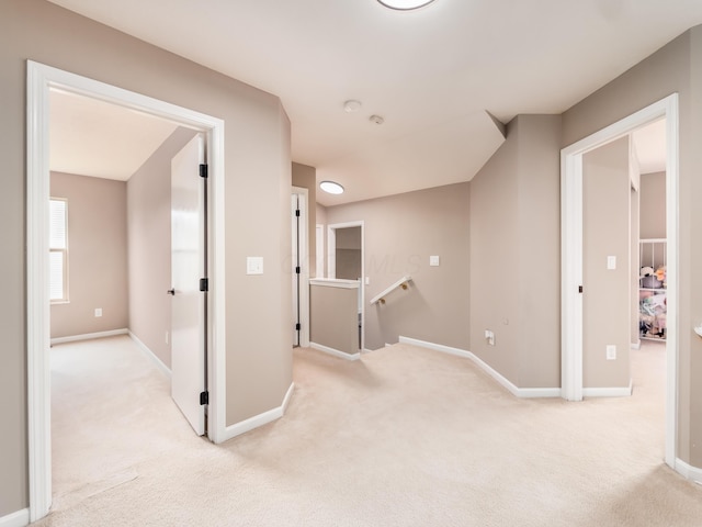 hall with light carpet, an upstairs landing, and baseboards