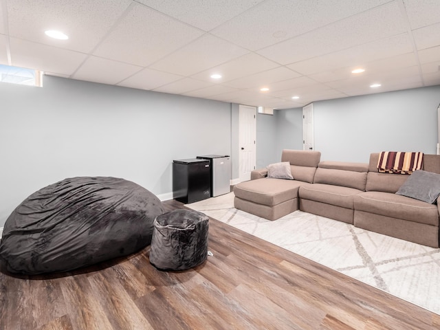 living area with recessed lighting, a paneled ceiling, and wood finished floors