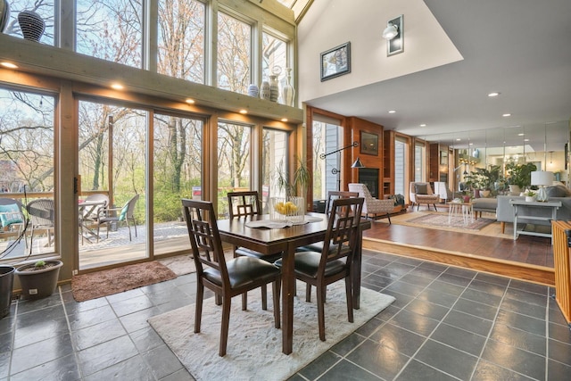 dining area with recessed lighting, a high ceiling, a healthy amount of sunlight, and a large fireplace