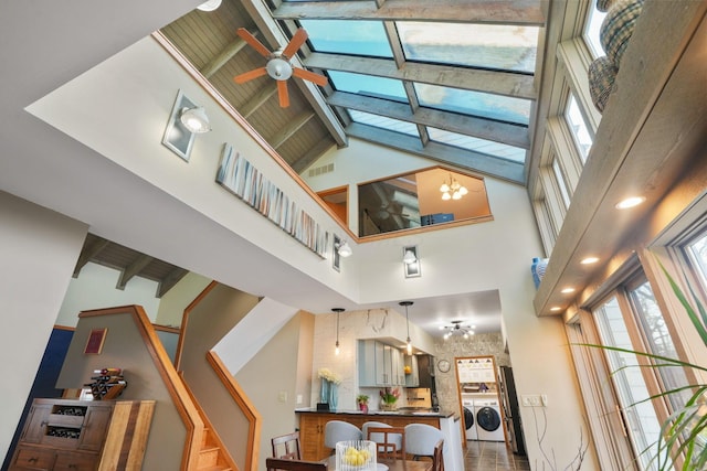living room with plenty of natural light, beam ceiling, high vaulted ceiling, and washing machine and clothes dryer