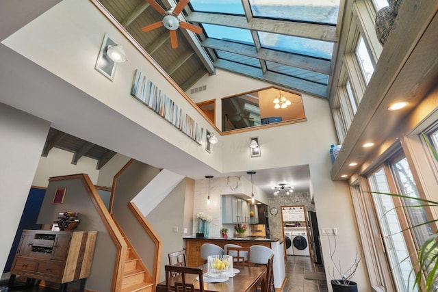 living area featuring a ceiling fan, independent washer and dryer, visible vents, high vaulted ceiling, and beamed ceiling