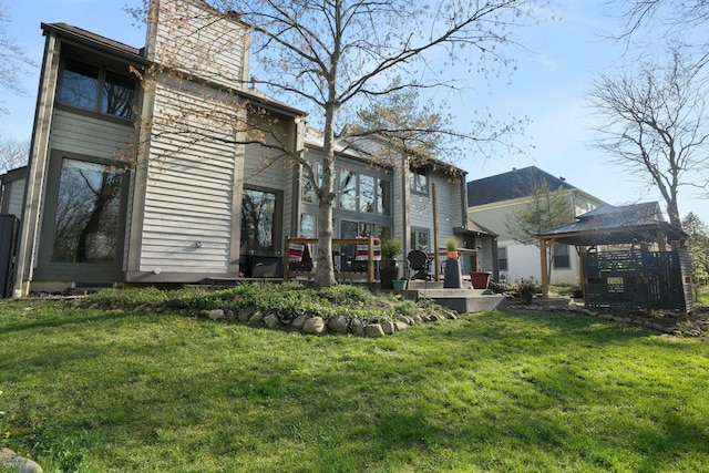 back of house featuring a lawn, a gazebo, and a chimney
