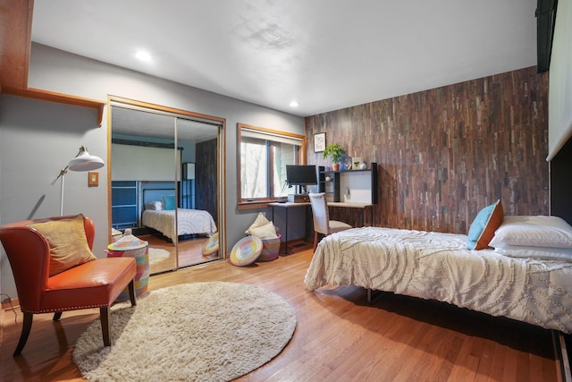 bedroom featuring a closet, wood walls, and wood finished floors
