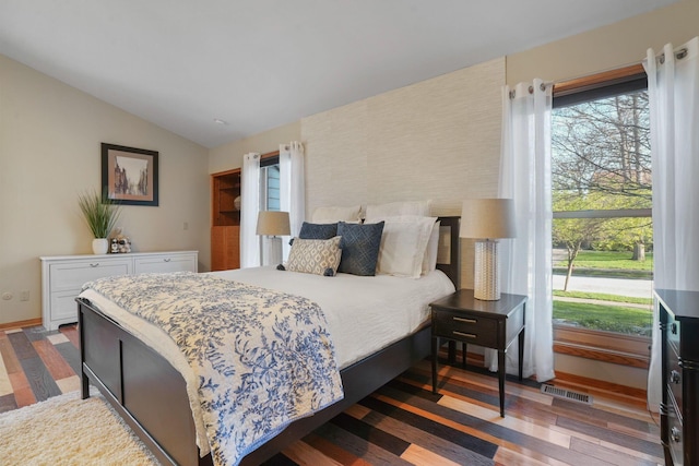 bedroom with visible vents, wood finished floors, and vaulted ceiling