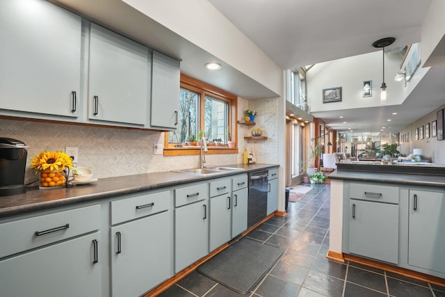 kitchen featuring dark countertops, hanging light fixtures, a sink, dishwasher, and decorative backsplash