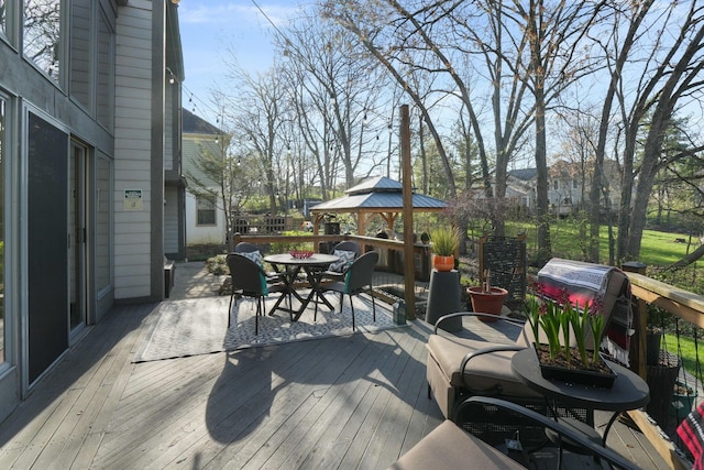 wooden terrace featuring a gazebo and outdoor dining space