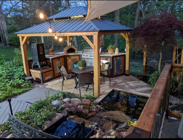 view of patio with a gazebo, an outdoor kitchen, a deck, outdoor dining area, and a grill