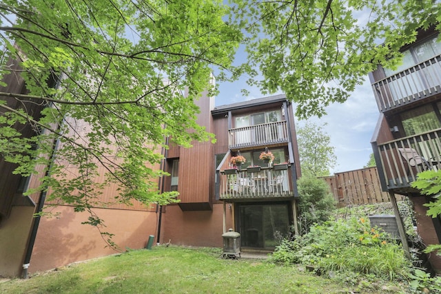 rear view of house with a lawn, a chimney, and a balcony