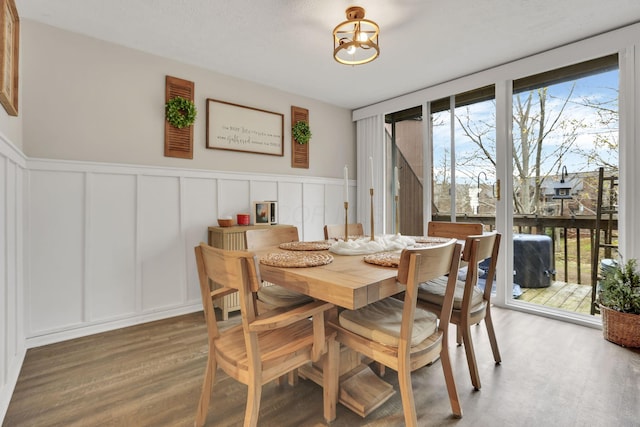 dining space with a wainscoted wall, a decorative wall, and wood finished floors