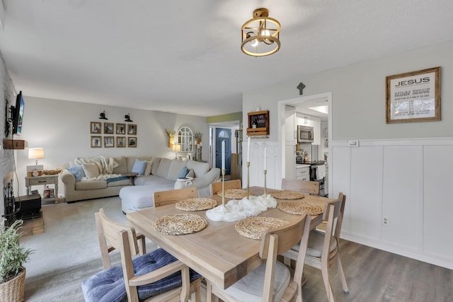 dining area with a decorative wall, a chandelier, dark wood-type flooring, and a wainscoted wall