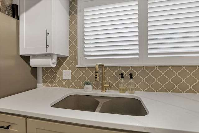 details with a sink, white cabinets, light stone countertops, and wallpapered walls