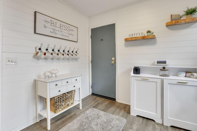 clothes washing area featuring wood finished floors and wooden walls