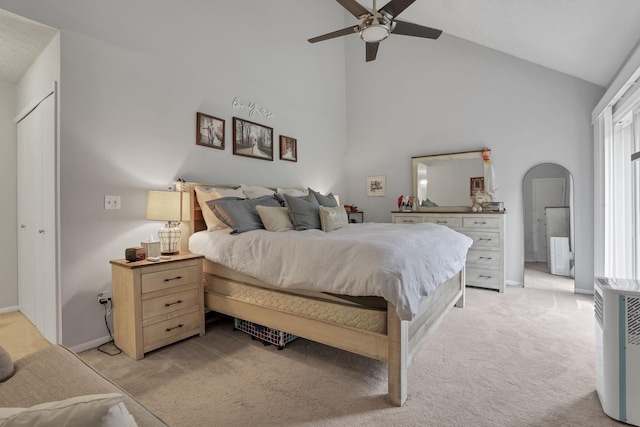 bedroom featuring baseboards, arched walkways, high vaulted ceiling, and light carpet