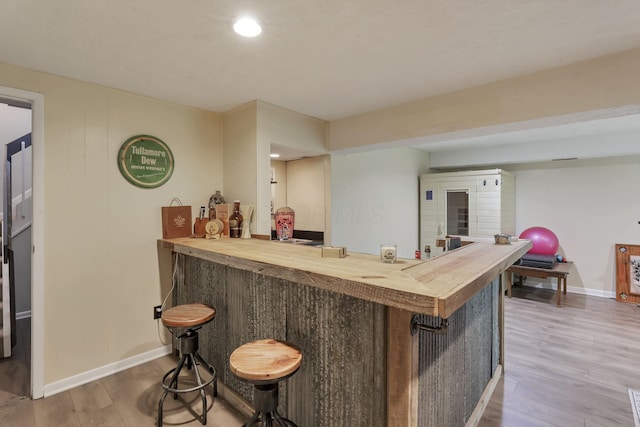 bar featuring recessed lighting, baseboards, bar, and wood finished floors
