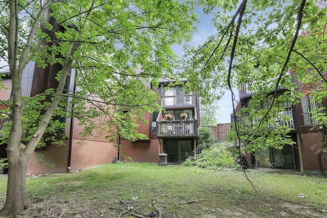 rear view of house featuring a lawn and a balcony