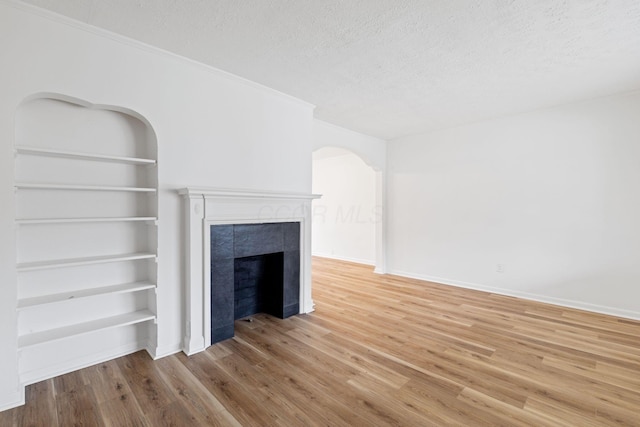 1381 Oakwood Ave, Columbus, OH 43206 - unfurnished living room with a textured ceiling, a tile fireplace, baseboards, wood finished floors, and built in shelves