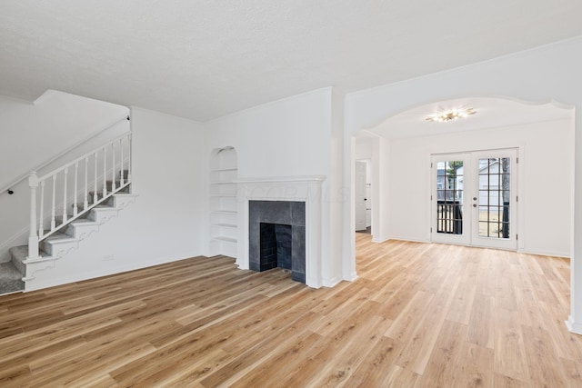 1381 Oakwood Ave, Columbus, OH 43206 - unfurnished living room featuring light wood-style flooring, arched walkways, stairs, and built in shelves