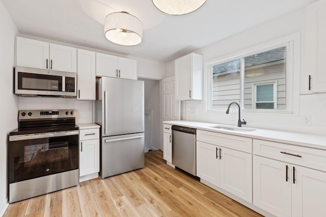 1381 Oakwood Ave, Columbus, OH 43206 - kitchen featuring light countertops, a sink, white cabinetry, stainless steel appliances, and light wood-style floors
