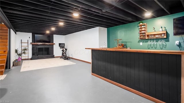 bar with concrete floors, indoor bar, baseboards, and a fireplace