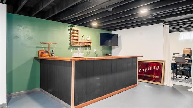 bar with baseboards, wet bar, and finished concrete floors
