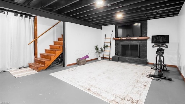 finished basement with baseboards, a fireplace, and stairway