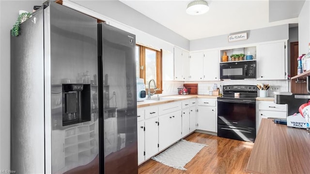 kitchen with light countertops, decorative backsplash, a sink, light wood finished floors, and black appliances