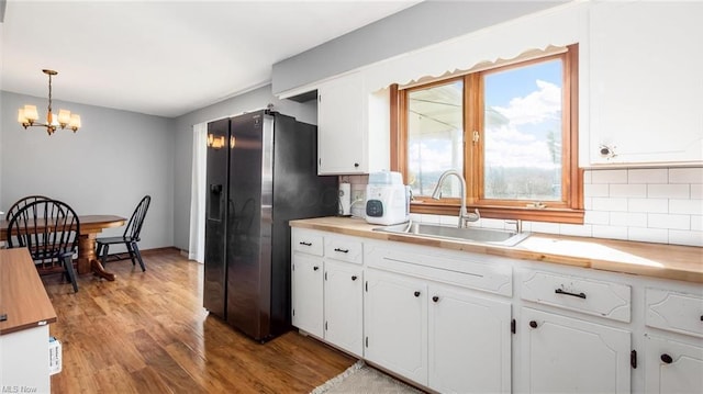kitchen with wood finished floors, tasteful backsplash, white cabinetry, a sink, and an inviting chandelier