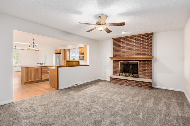 306 Northview Dr, London, OH 43140 - unfurnished living room with light colored carpet, a fireplace, ceiling fan with notable chandelier, baseboards, and visible vents
