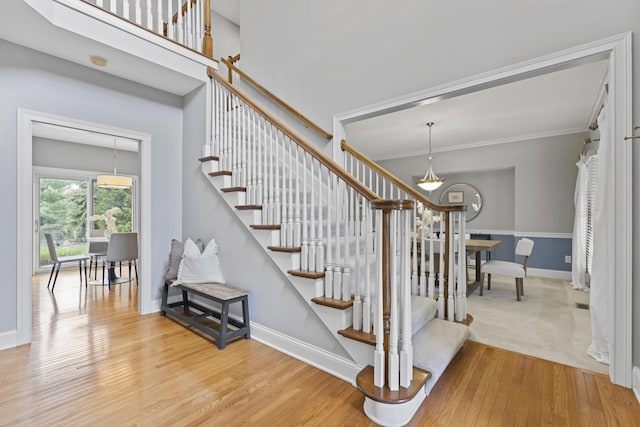 stairs featuring crown molding, wood finished floors, and baseboards