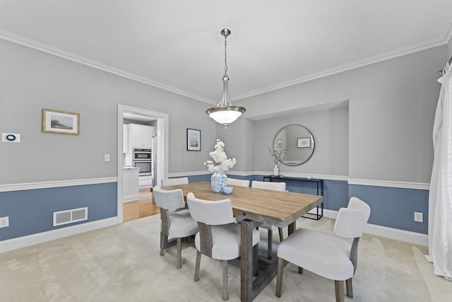dining room featuring ornamental molding, light carpet, baseboards, and visible vents