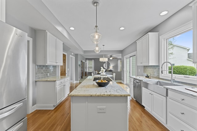 kitchen with a healthy amount of sunlight, stainless steel appliances, light wood-style flooring, and a center island