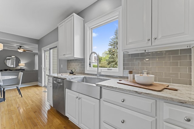 kitchen featuring light wood-style flooring, dishwasher, a sink, white cabinetry, and open floor plan