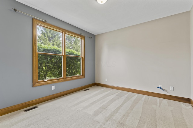 empty room featuring carpet, visible vents, and baseboards