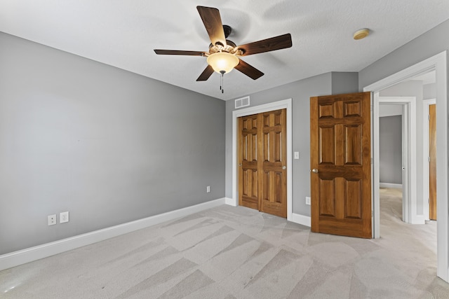 unfurnished bedroom featuring a ceiling fan, a closet, visible vents, baseboards, and light carpet