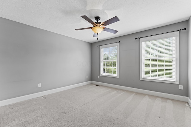 carpeted empty room with a textured ceiling, visible vents, baseboards, and a ceiling fan