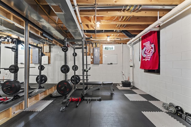 workout area with concrete block wall and electric panel