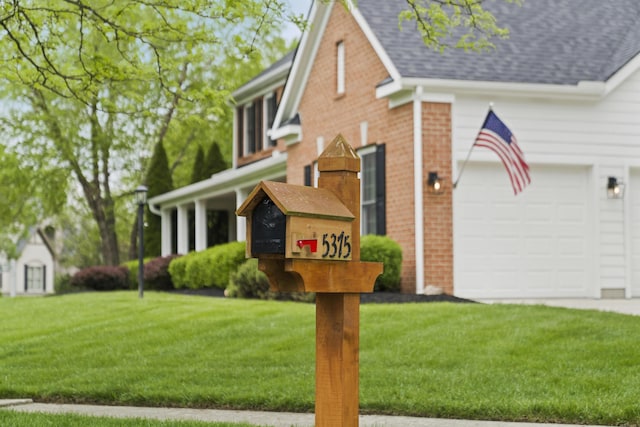traditional home featuring a shingled roof, brick siding, an attached garage, and a front lawn